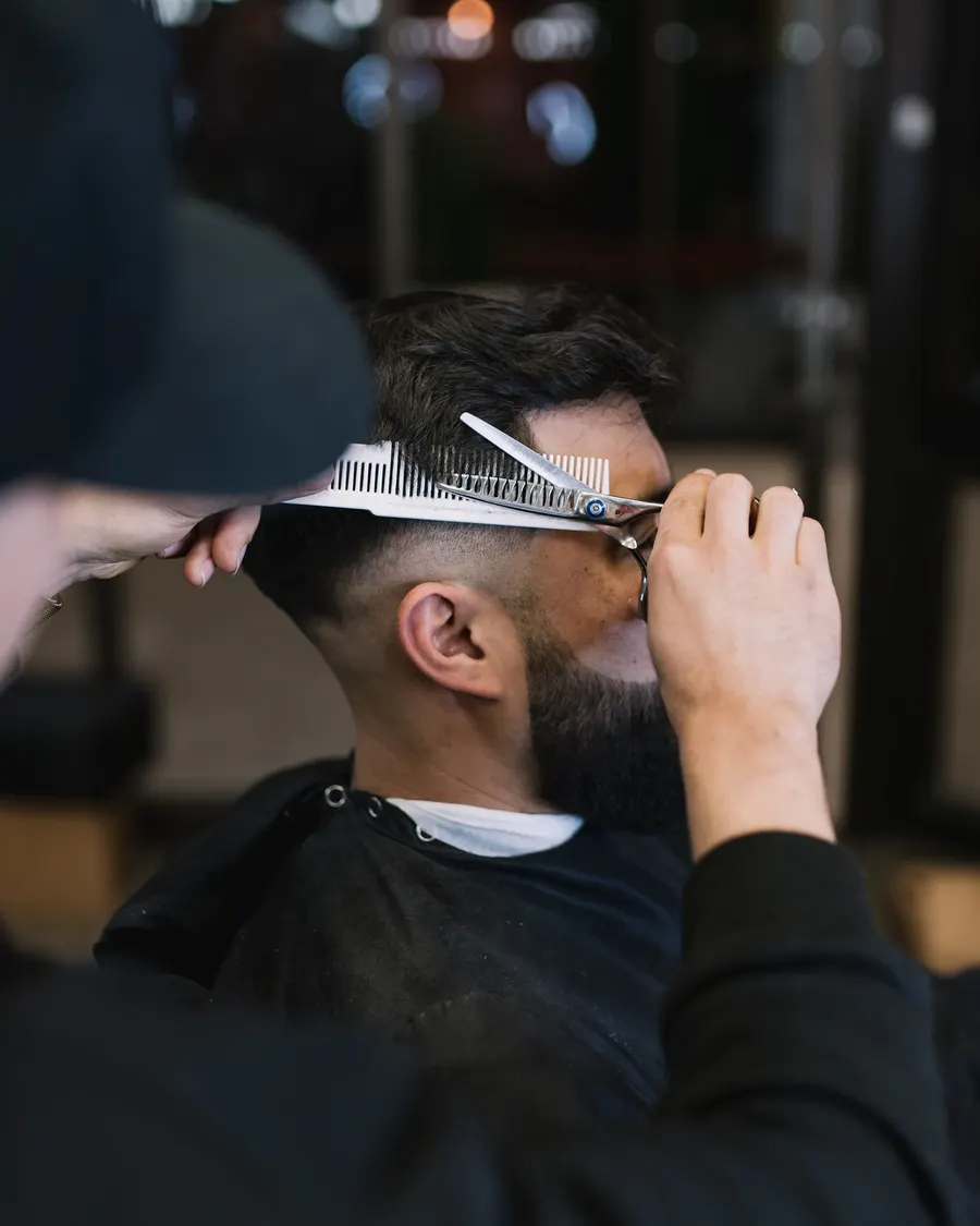 Barber finishing a skin fade with a straight razor